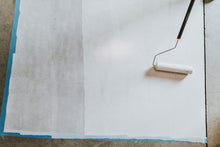 Load image into Gallery viewer, White paint being applied to concrete floor with a roller